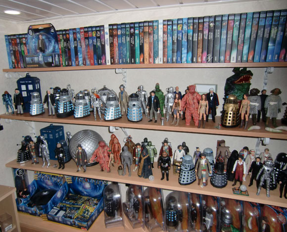 Doctor Who merchandise image featuring monster, companion anddoctor figures, the TARDIS, sonic screwdriver and VHS. These are set across 4 shelves.